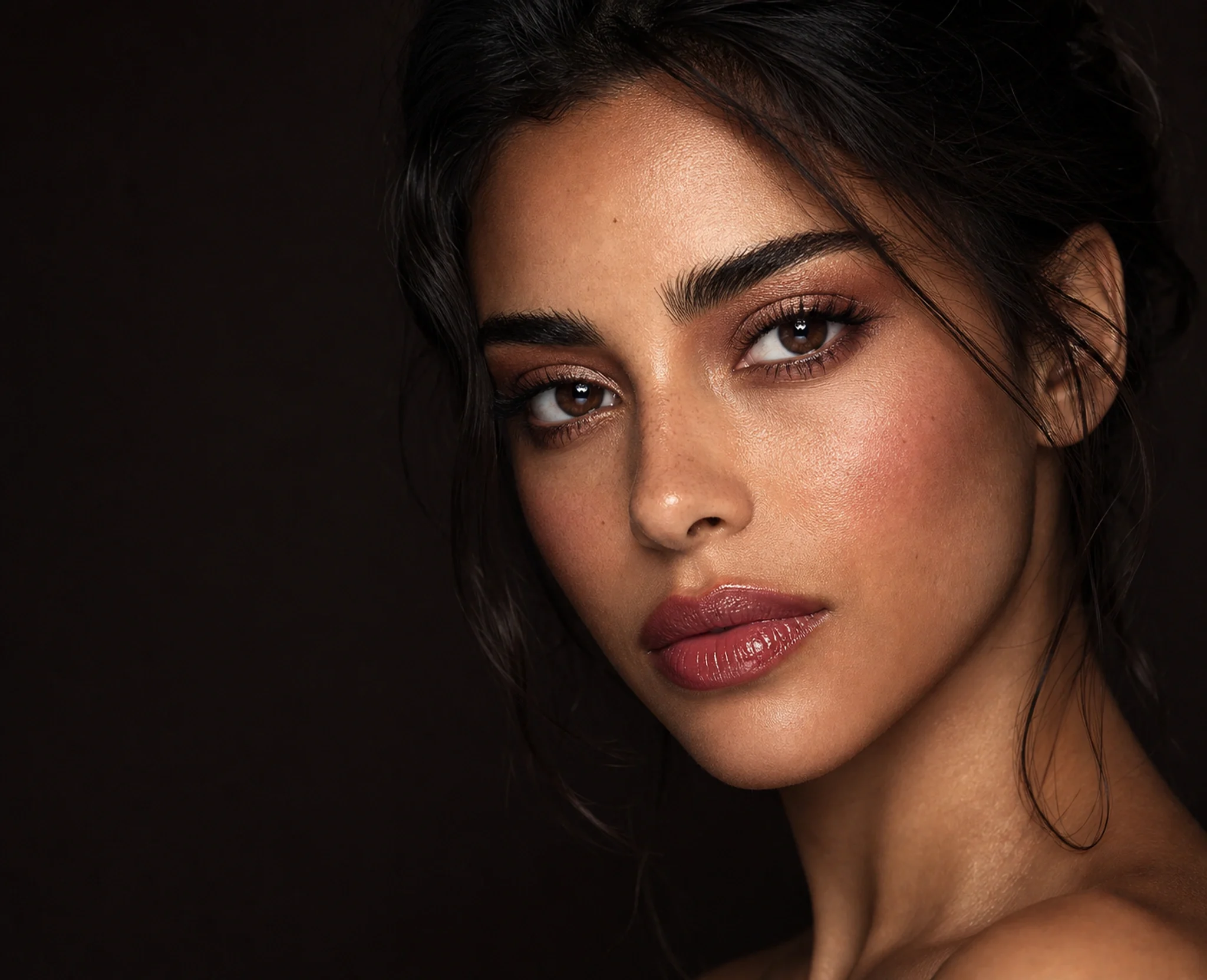 Close-up beauty editorial with copper-mauve eyes, rosewood glossy lips, and visible natural skin texture