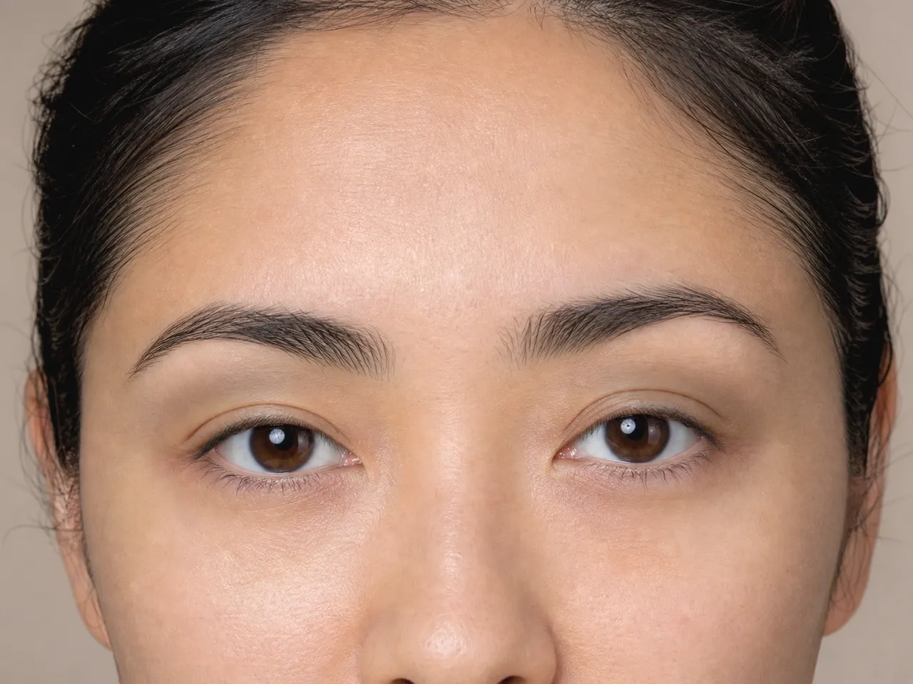 Step 2 of Soft Glam for Hooded Eyes, showing visible taupe creates a soft guide at just above the hood fold that remains visible with a relaxed gaze.