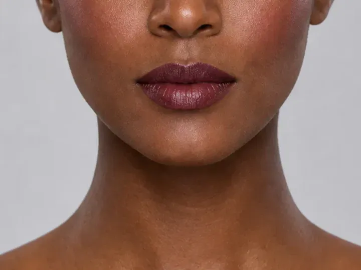 Step 6 of Rich Berry and Gold Makeup for Deep Skin, showing deep berry is visible at upper cheek and lips while natural skin still shows through the edges.